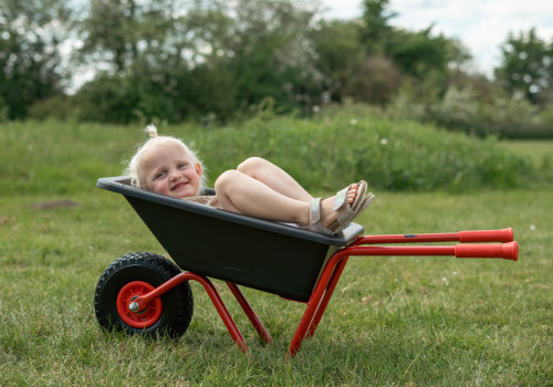 Roze kruiwagen met één wiel, kunststof bak en rubberen handgrepen, ideaal voor kinderen om mee te spelen.