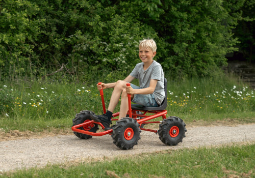 ROSE gokart met tractorbanden, robuuste kunststof zitting, jongen rijdt op een pad omringd door groen. Geschikt voor 3-6 j...