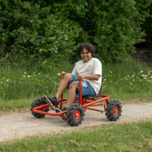ROSE gokart met tractorbanden, robuuste zitting en achterwielbesturing, gebruikt door een kind op een pad.
