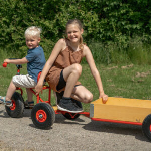 Grote ROSE aanhanger met houten bak en massieve banden, bevestigd aan een driewieler, met kinderen die erop zitten.