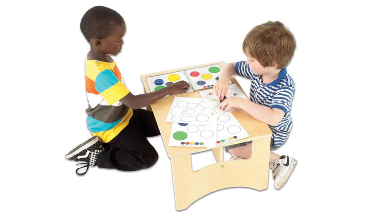 Kinderen spelen aan een lichte speeltafel met kleurpotloden en tekeningen, ideaal voor creatief leren.