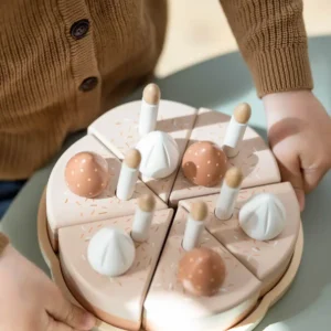 Verjaardagstaart met zes stukken, kaarsjes en decoraties, vastgehouden door een kind. Perfect voor speelhoeken.