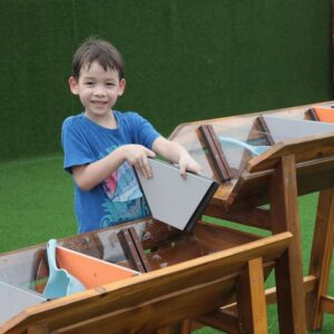 Kinderen spelen met de Waterbaan Outdoor XL, leren over waterstroming op een groene ondergrond.
