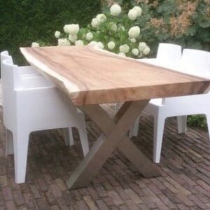 Boomstamtafel met robuust houten blad en stabiele metalen basis, omringd door witte stoelen in een groene omgeving.
